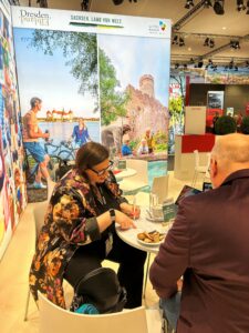Das Foto zeigt Chiara Gasparini von der TMGS im Gespräch mit einem Fachbesucher am Messestand