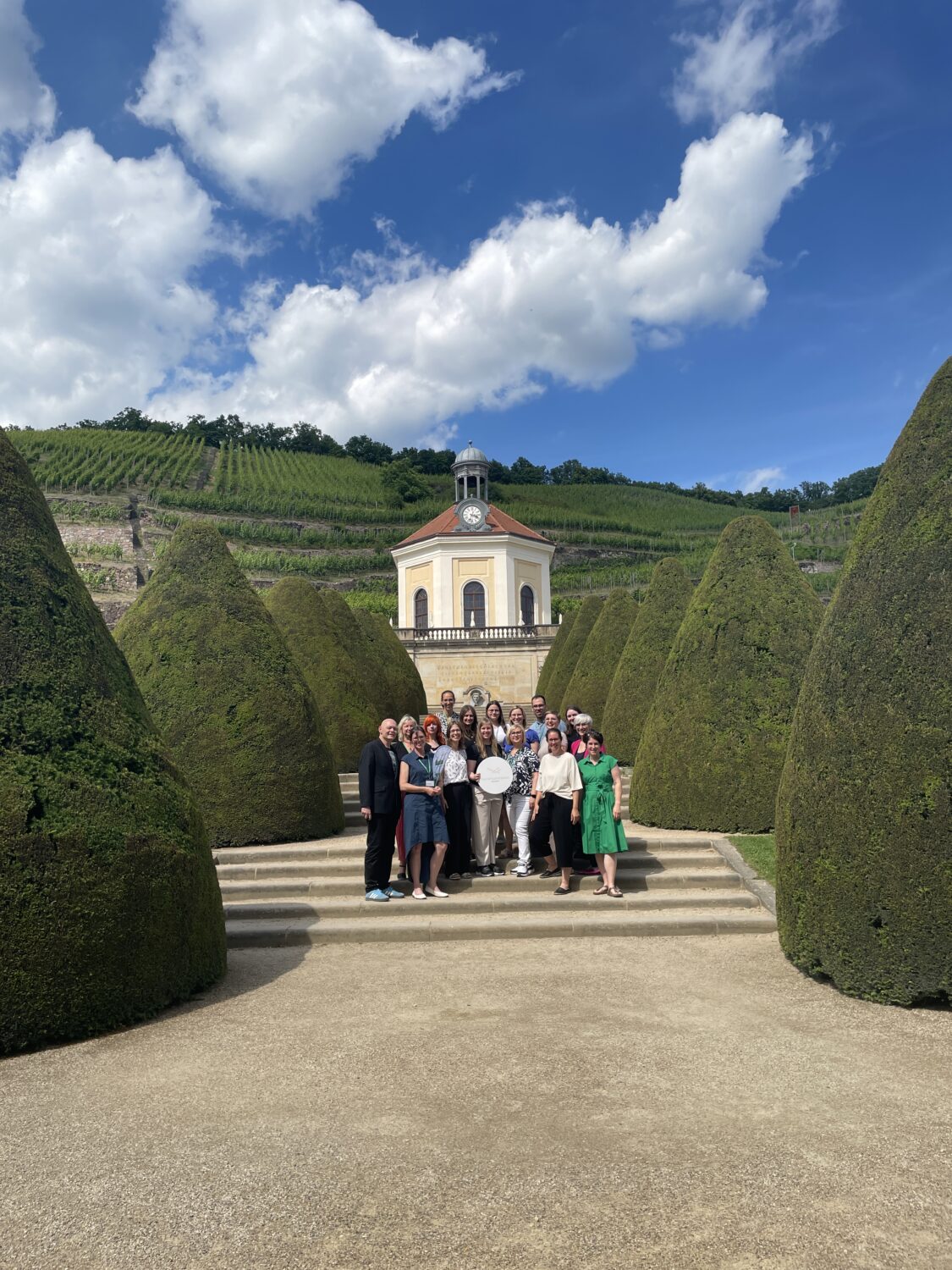 Die Teilnehmenden des Netzwerkpartnertreffens stehen als Gruppe auf einer Treppe vor dem Belvedere auf Schloss Wackerbarth